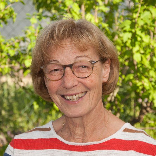 Eine Frau mit Brille und gestreiftem Hemd lächelt in die Kamera.