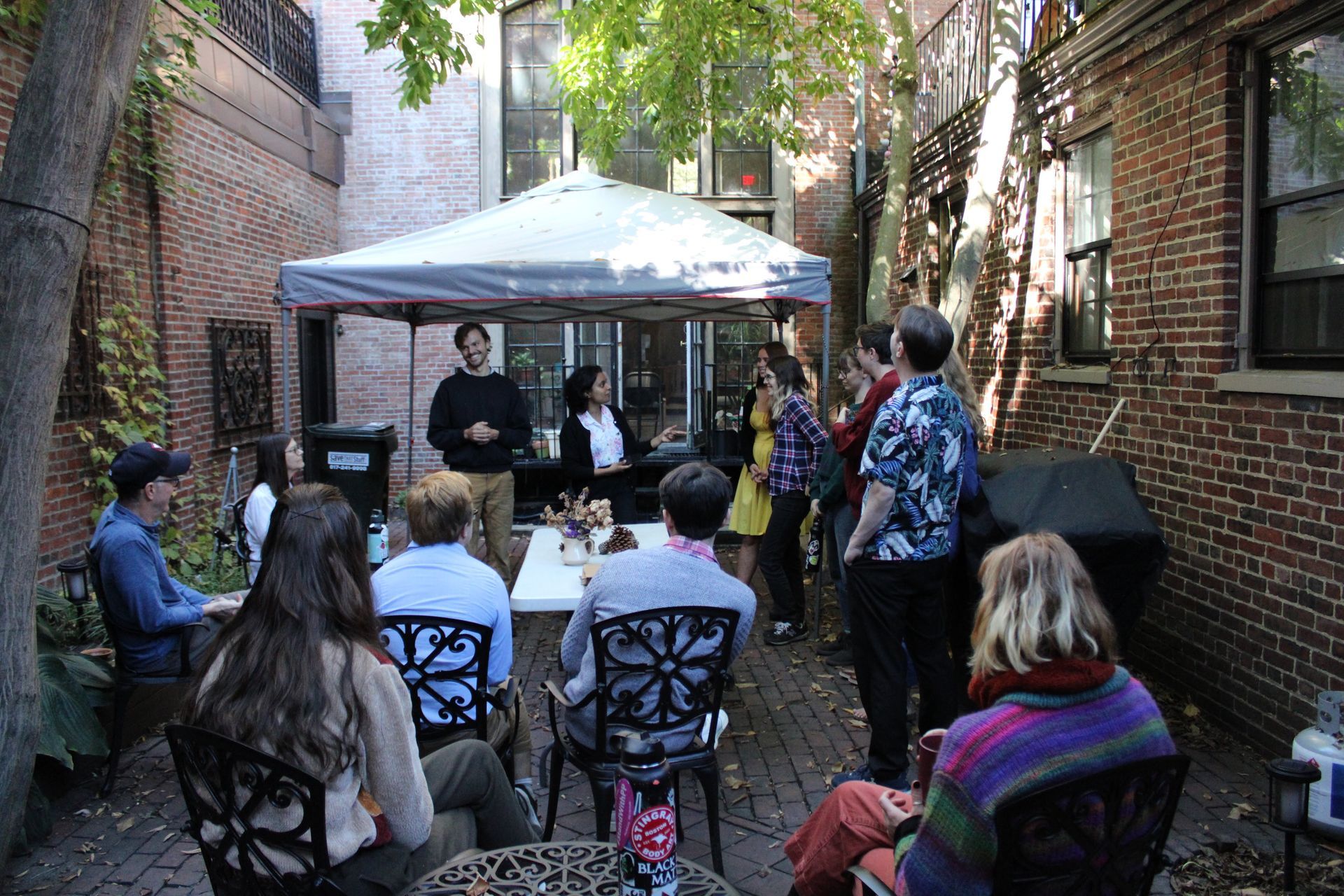 A group of people gathers in a brick courtyard under a tent.