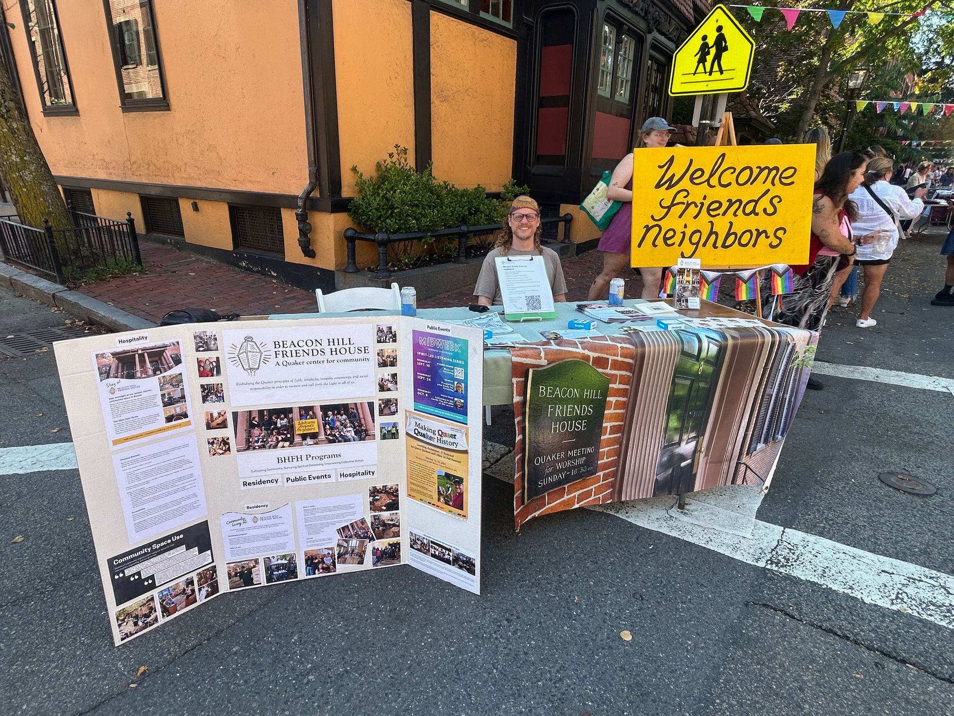 A person sits at a table on a sidewalk with a