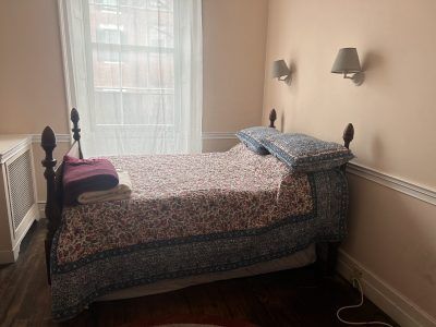 A queen four post bed in a bright room.