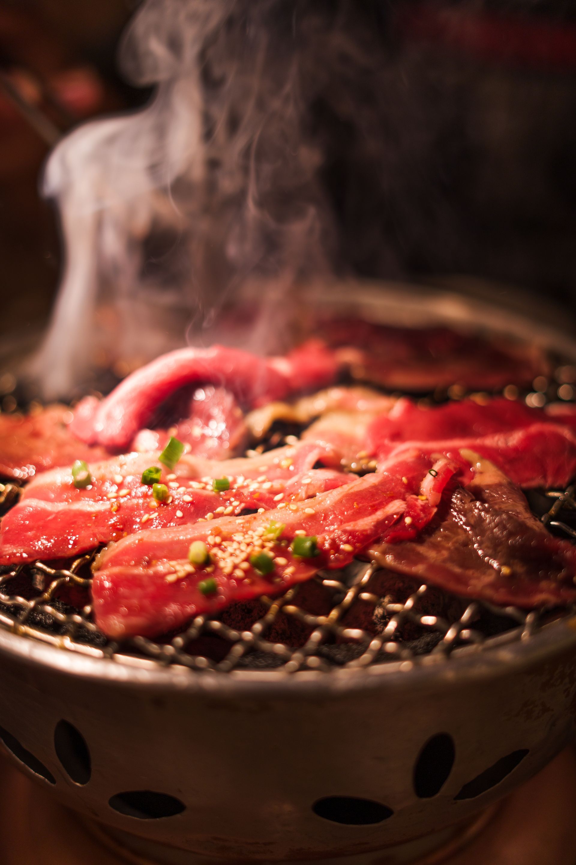 JPOT Japanese BBQ sliced beef being cooked on the table grill, still raw with smoke coming up from the meat