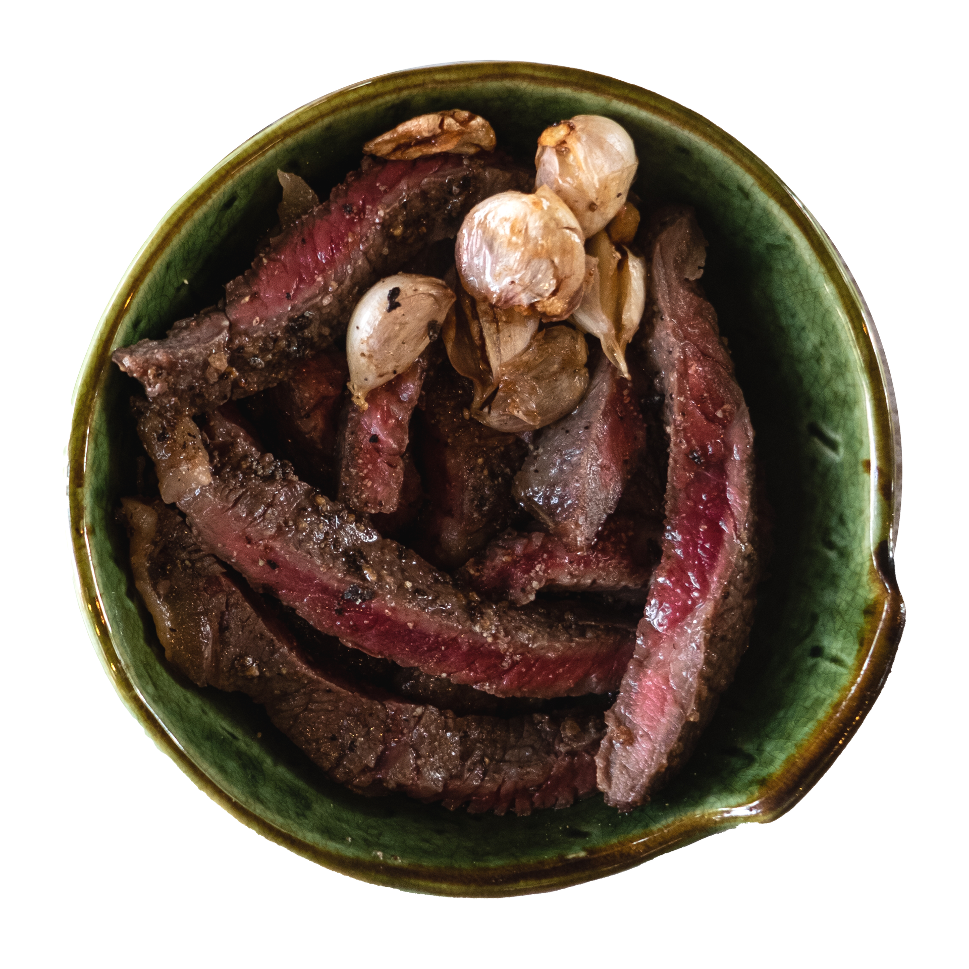 JPOT Japanese BBQ cut up and sliced medium rare galbi short ribs with garlic cloves in a green ceramic bowl  bird's eye view