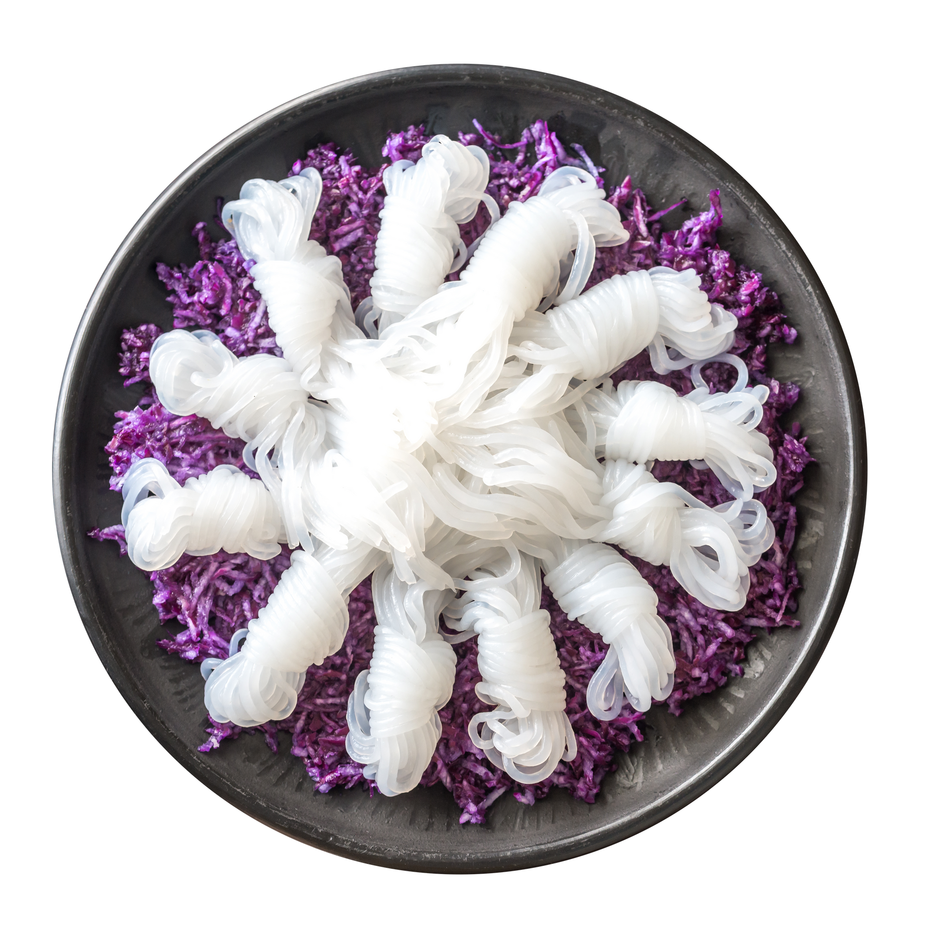 JPOT Japanese hot pot shirataki noodle knots over shredded red cabbage on black plate bird's eye view