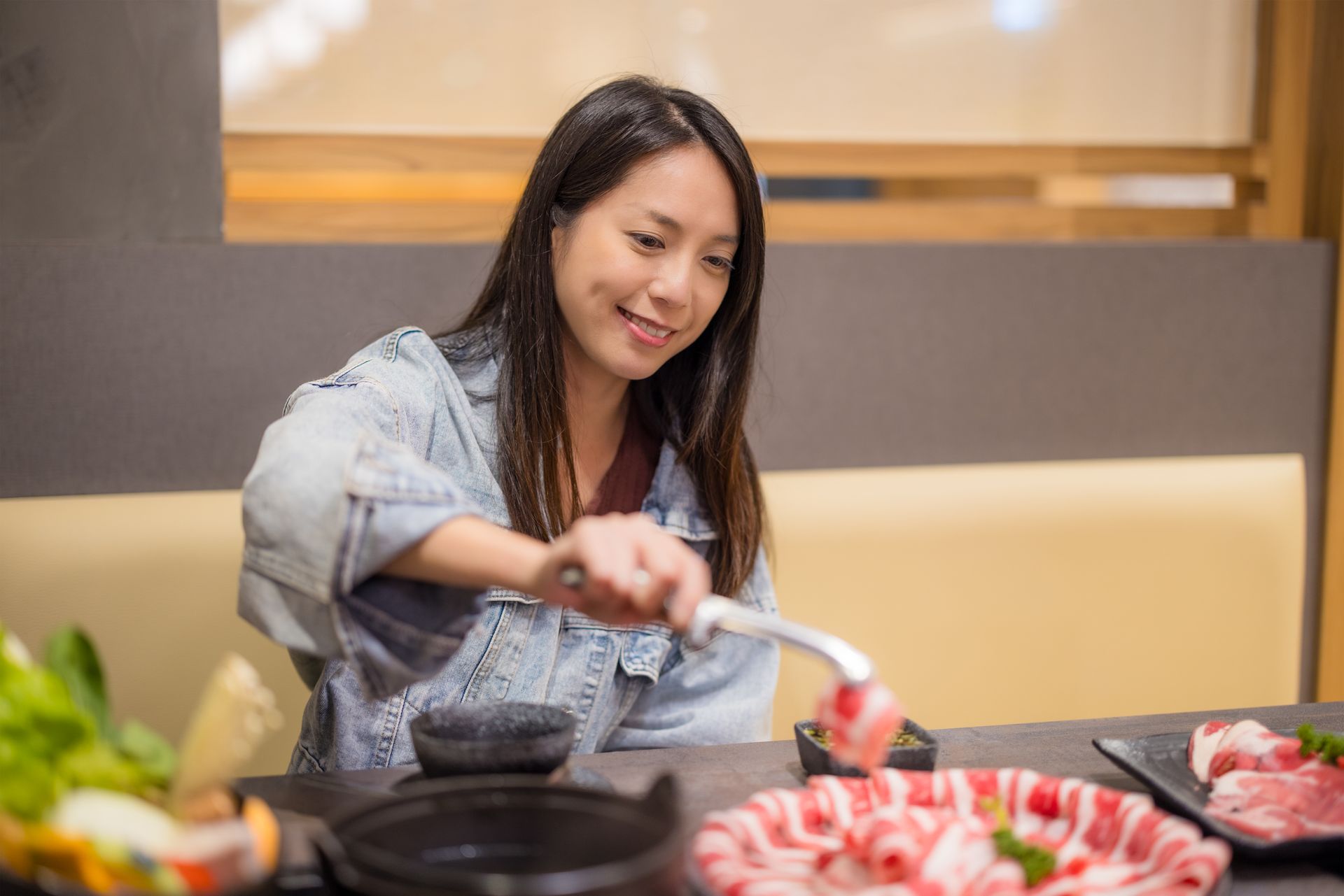 JPOT Japanese hot pot happy asian woman using tongs to grab raw meat to put into hot pot broth to cook 