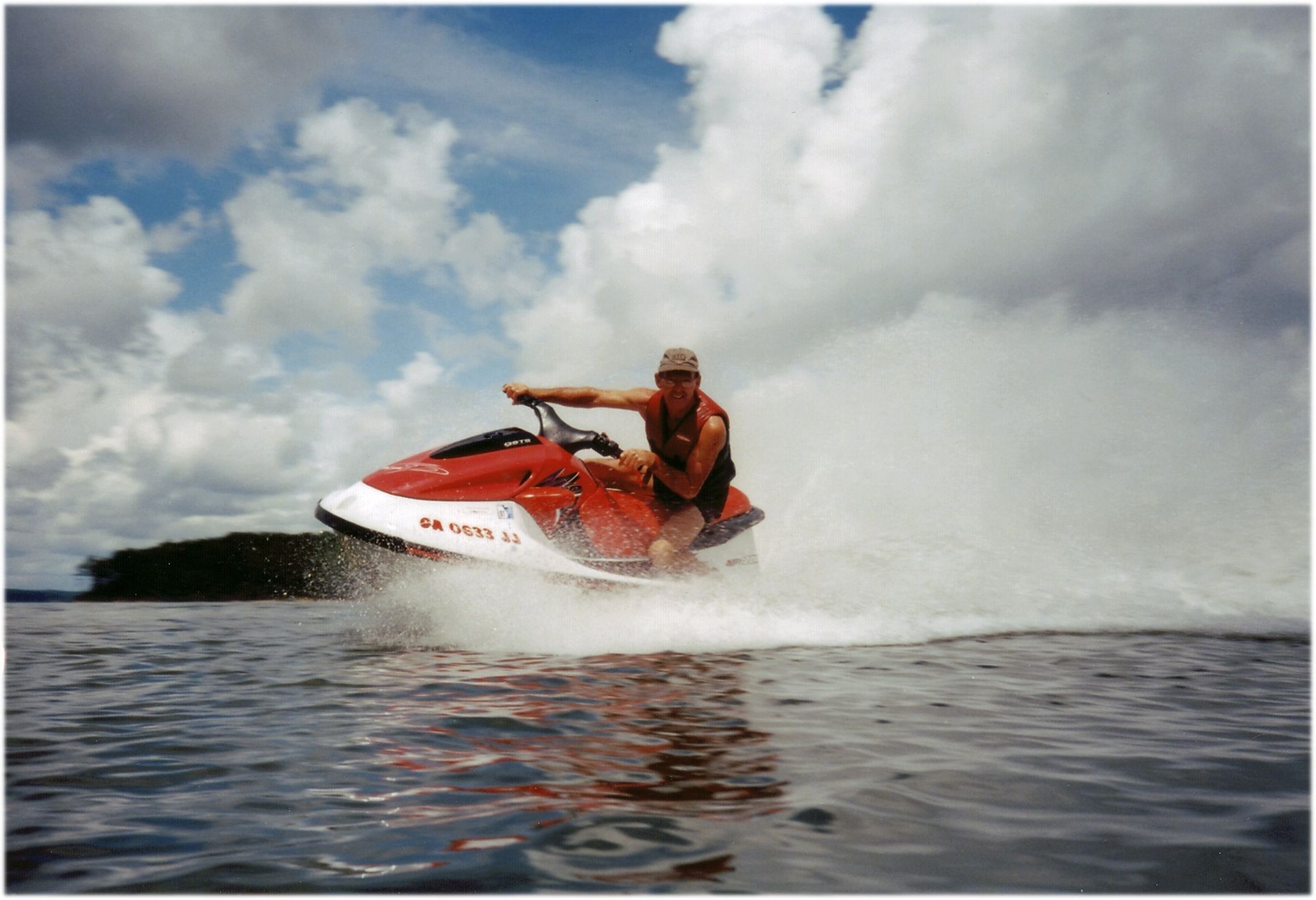 A man is riding a red and white jet ski in the water