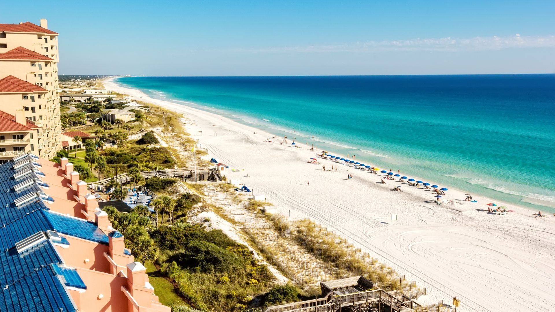 An aerial view of a beach with a hotel in the background.