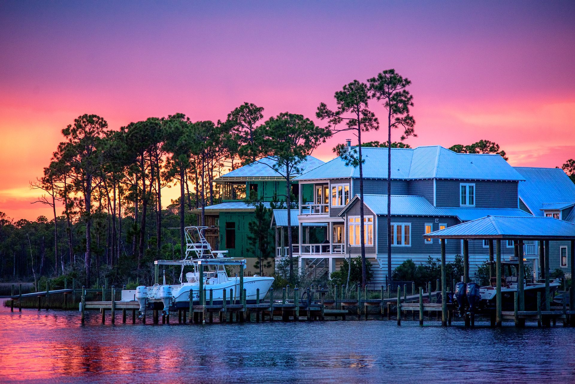 A group of houses sitting on top of a body of water at sunset.