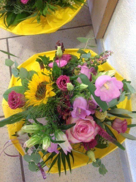 Zwei gelbe Regenschirme gefüllt mit rosa und gelben Blumen