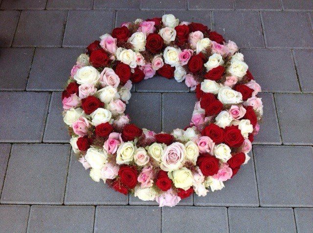 Ein Kranz aus roten und weißen Rosen auf einem Ziegelboden