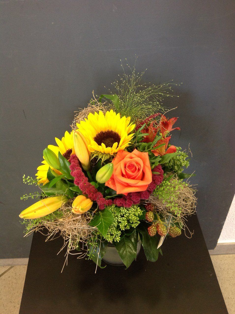 Eine Vase gefüllt mit Blumen, darunter Sonnenblumen und Rosen