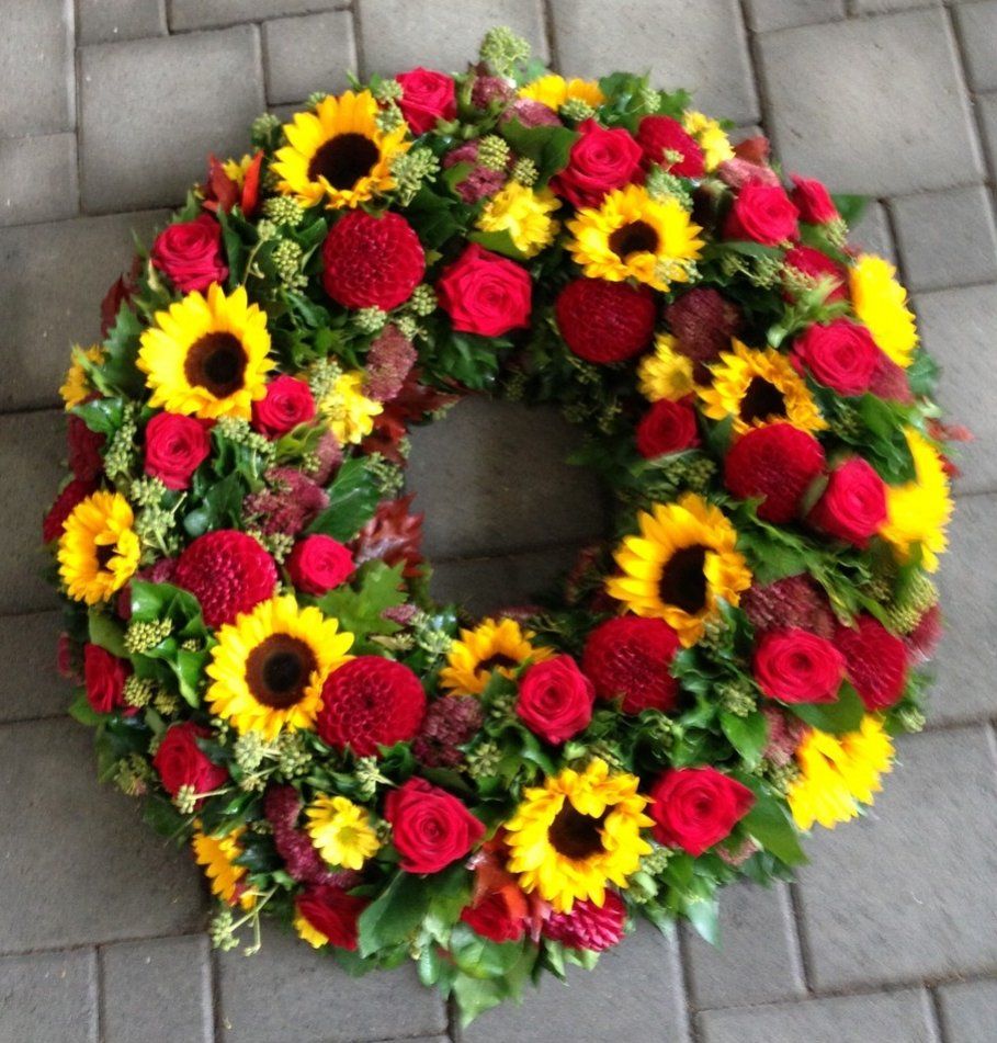 Ein Kranz aus roten und gelben Blumen auf einem Ziegelboden