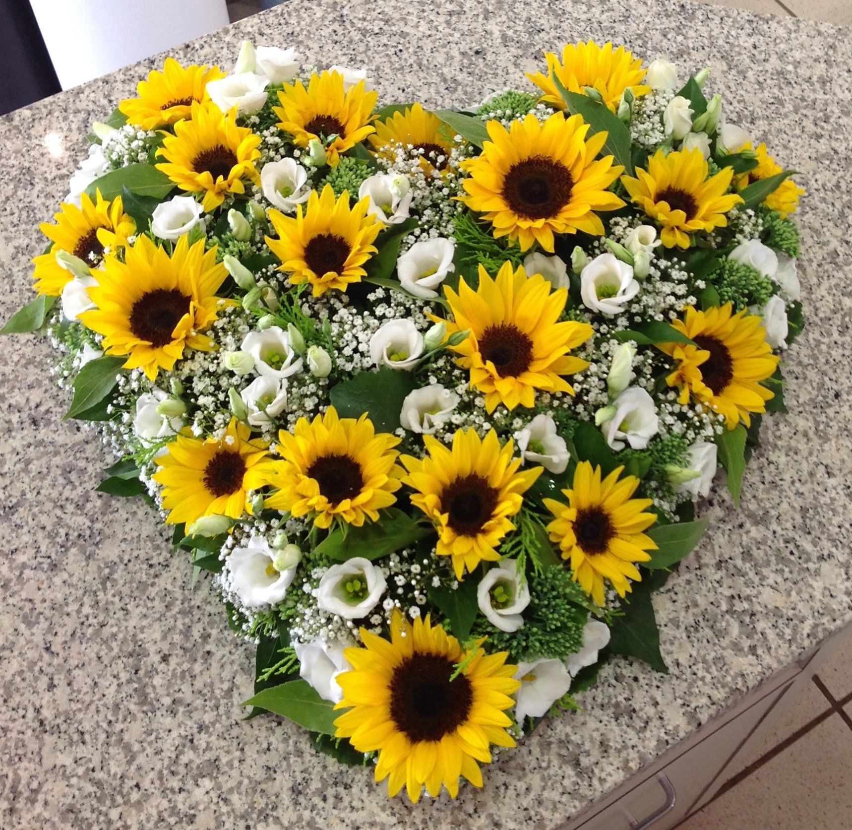 Ein herzförmiges Arrangement aus Sonnenblumen und Schleierkraut