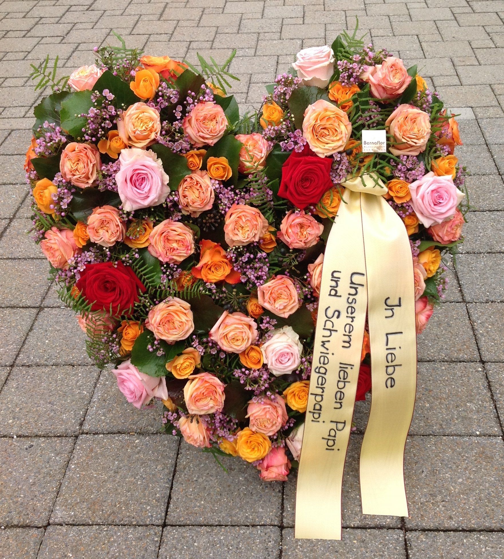 Ein herzförmiger Blumenkranz mit einer Schleife mit der Aufschrift „Ich liebe“