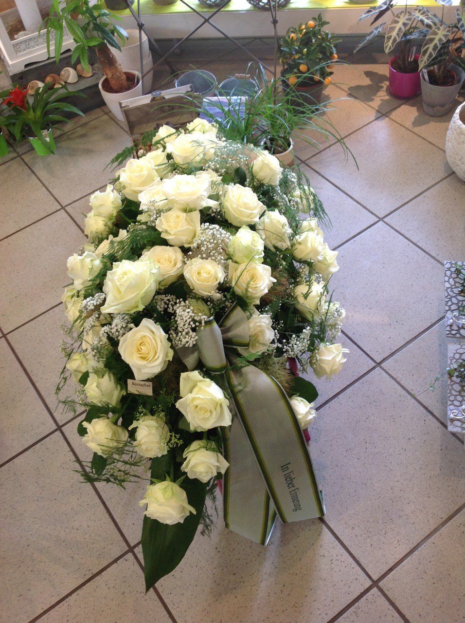 Ein Strauß weißer Rosen liegt auf einem gefliesten Boden.