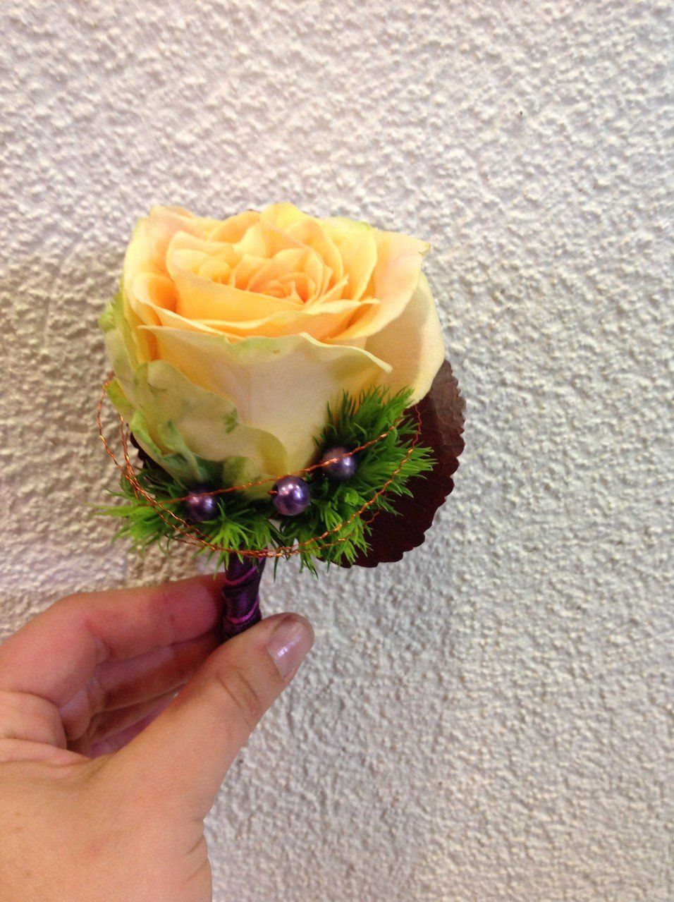 Eine Person hält eine einzelne gelbe Rose an einem violetten Stiel.