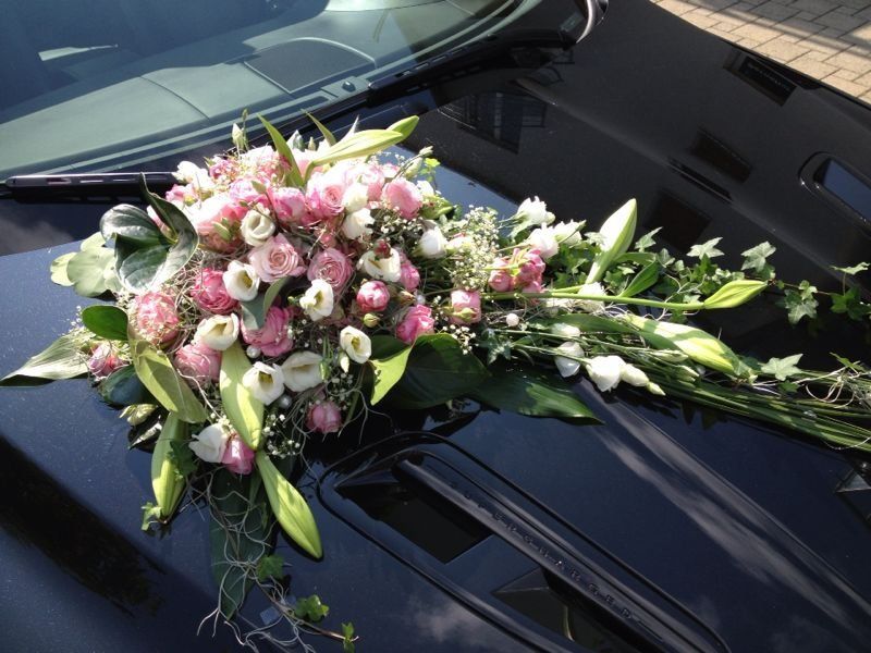 Ein schwarzes Auto mit rosa und weißen Blumen auf der Motorhaube