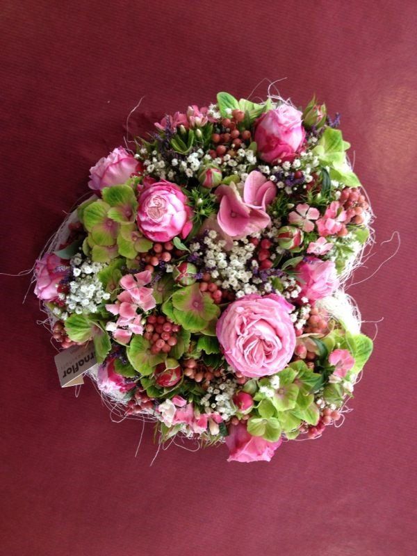 Ein Strauß rosa und grüner Blumen auf einer roten Oberfläche.