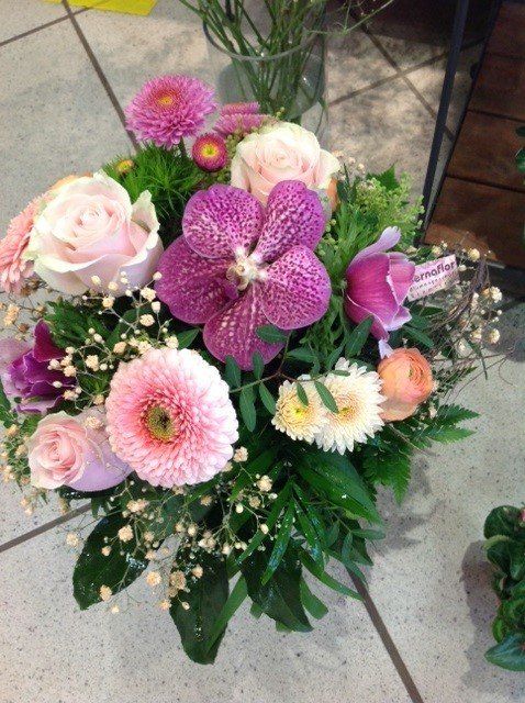 Ein Strauß rosa und lila Blumen auf einem gefliesten Boden