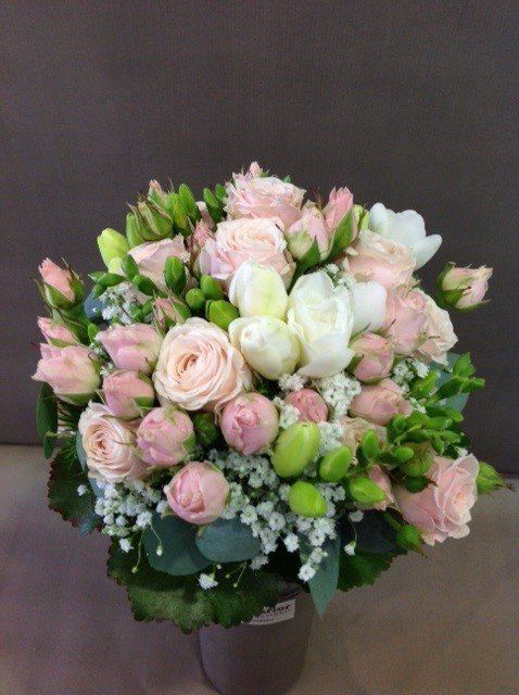 Auf einem Tisch steht eine Vase mit rosa und weißen Blumen.