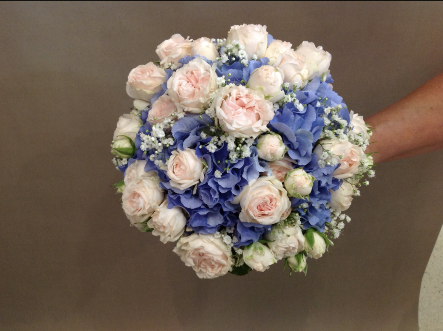 Eine Person hält einen Strauß blauer und weißer Blumen