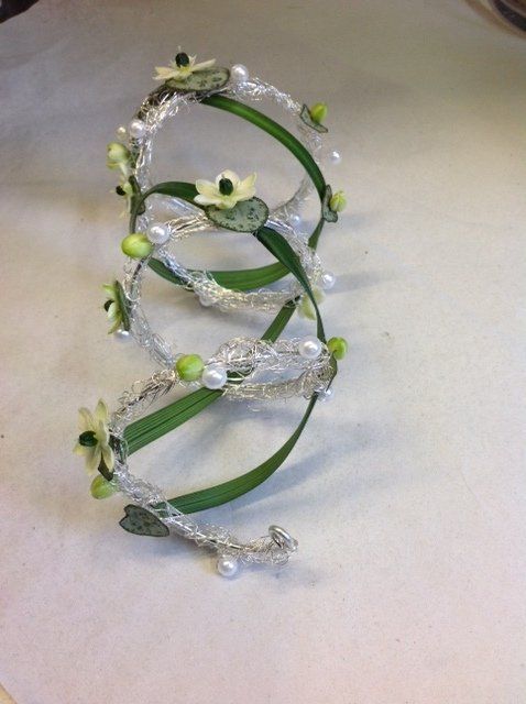 Eine Spirale mit Blumen und Perlen auf weißem Untergrund