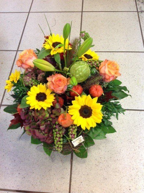 Ein Korb mit Sonnenblumen und Rosen steht auf einem gefliesten Boden
