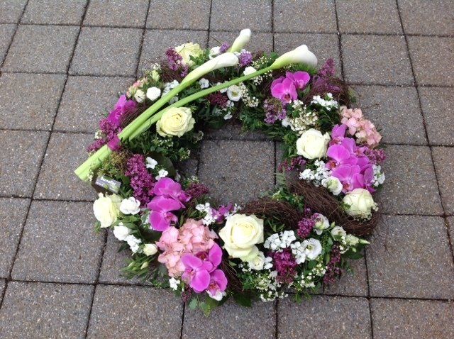 Auf einem gefliesten Boden liegt ein Blumenkranz.