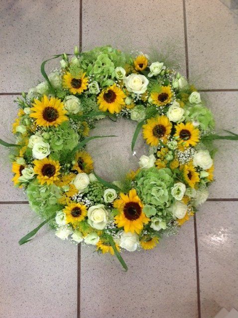 Ein Kranz aus gelben und grünen Blumen auf einem gefliesten Boden