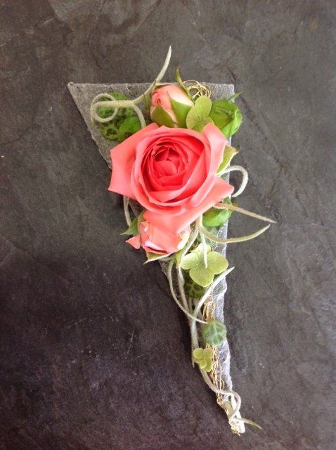 Eine rosa Rose liegt in einem Dreieck auf einem Tisch