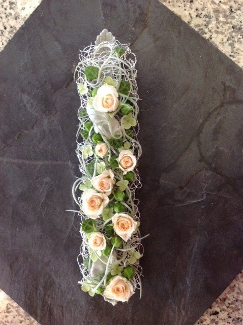 Der Buchstabe i ist mit weißen Rosen und Grün geschmückt