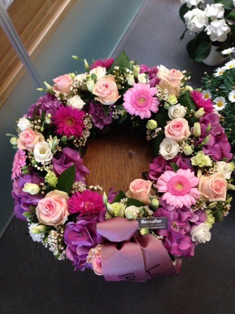 Ein Kranz aus rosa und lila Blumen auf einem Tisch