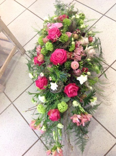 Auf einem gefliesten Boden steht ein Strauß rosa und grüner Blumen.