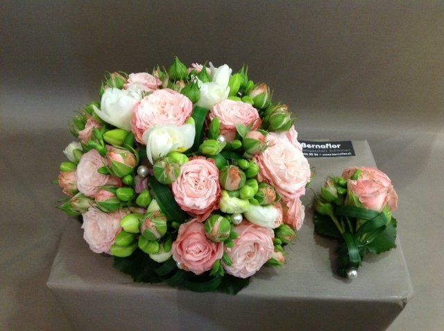 Auf einer Kiste steht ein Strauß rosafarbener und weißer Blumen.