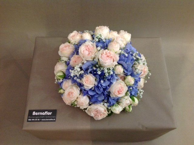 Auf einer Kiste steht ein Strauß rosa und blauer Blumen.