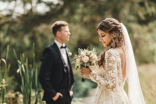 Eine Braut und ein Bräutigam posieren für ein Foto, während die Braut einen Blumenstrauß hält.