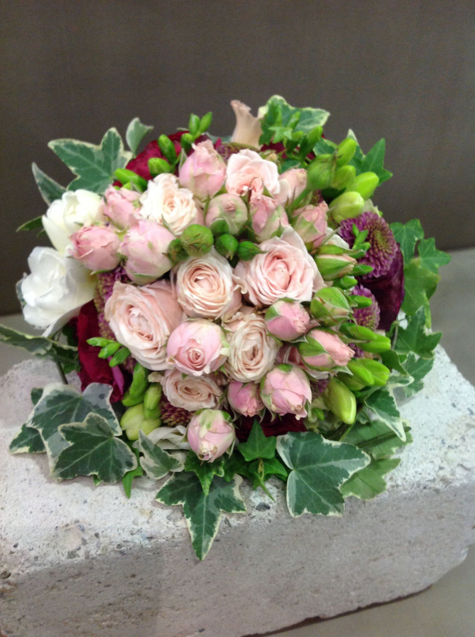 Ein Strauß rosa und weißer Blumen sitzt auf einem Ziegelstein