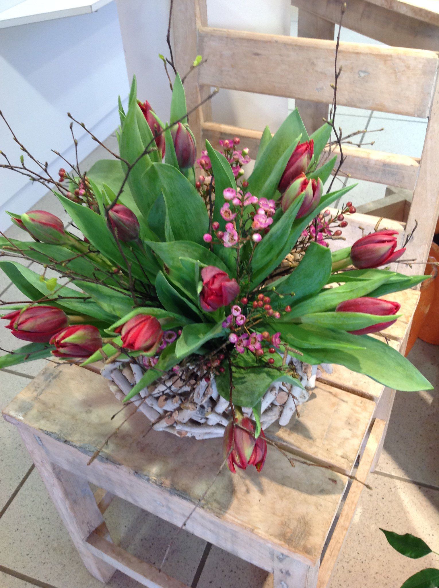 Auf einem Holzstuhl steht ein Blumenstrauß.