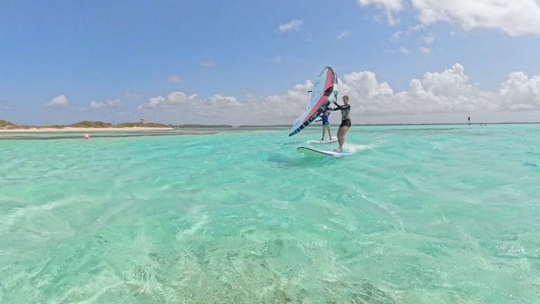 A man and a woman are windsurfing in the ocean in the Caribbean