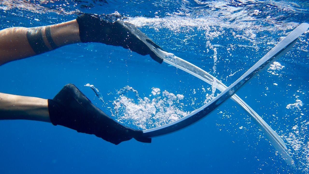 A person is holding a pair of wiper blades underwater.