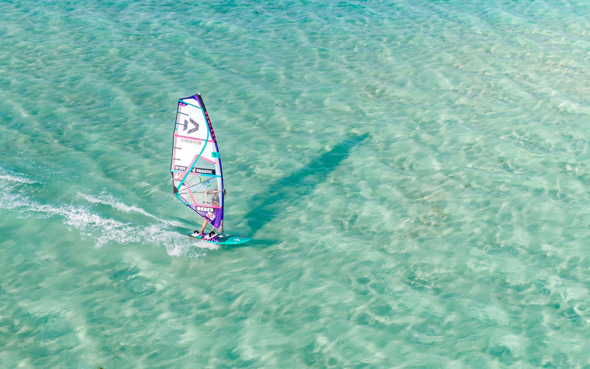 An aerial view of a person windsurfing in the ocean. Best place for windsurfing.