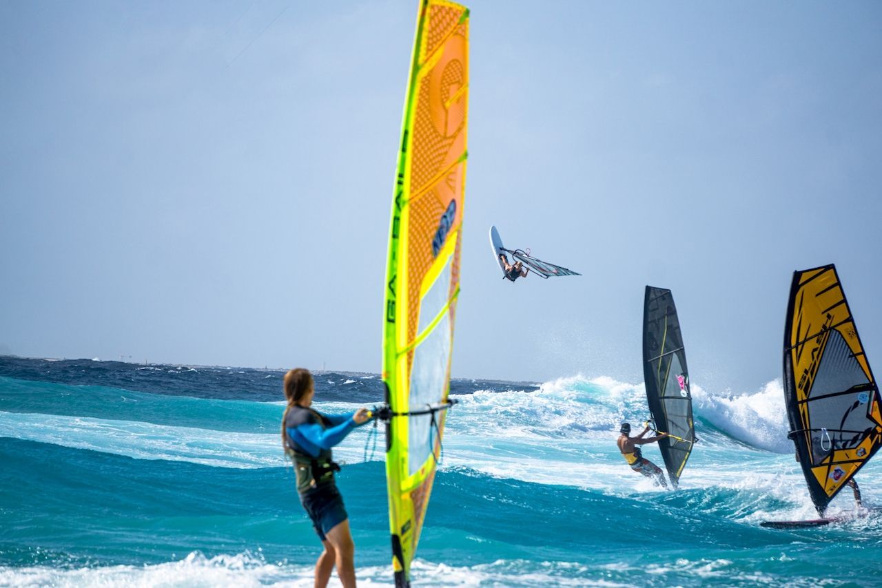 A group of people are windsurfing in the ocean, best place for windsurfing.