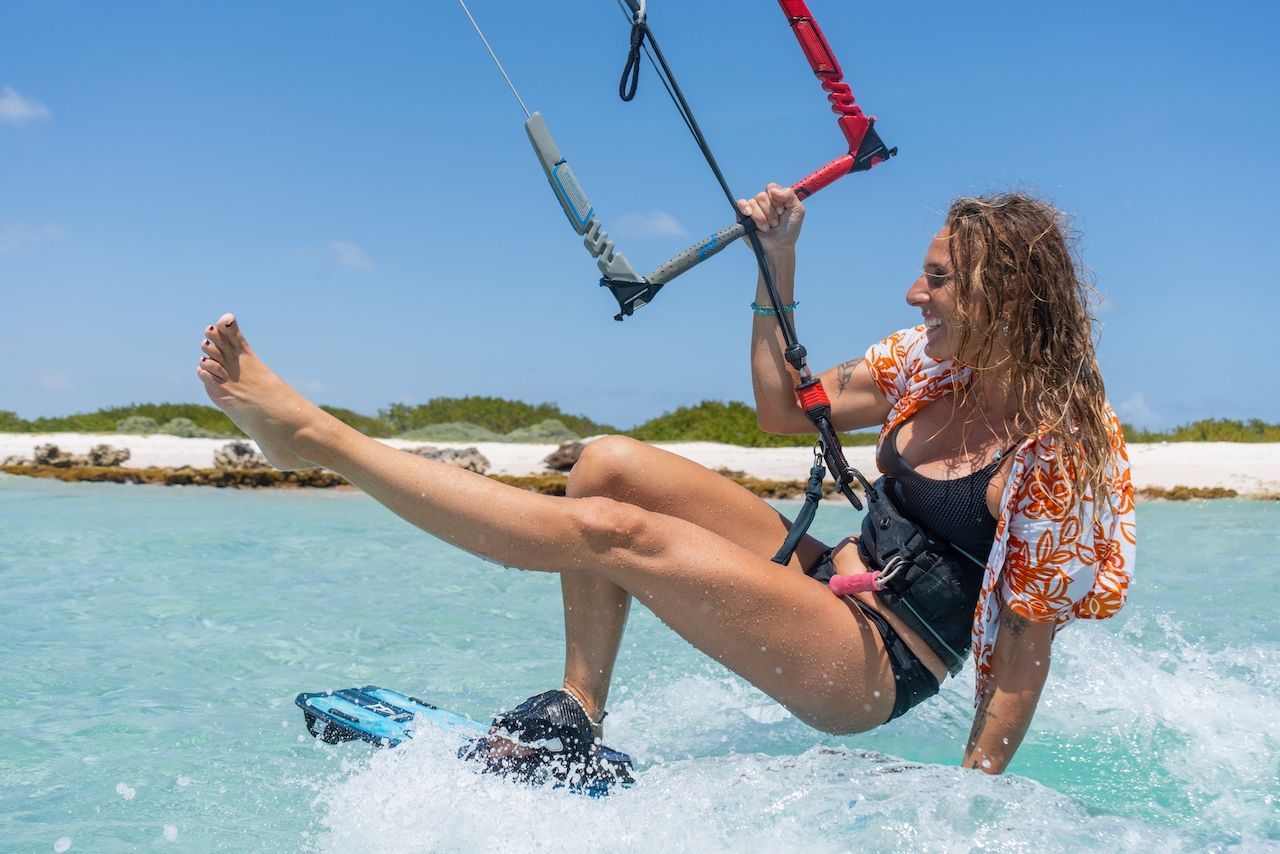 A woman in a bikini is flying a kite in the ocean.