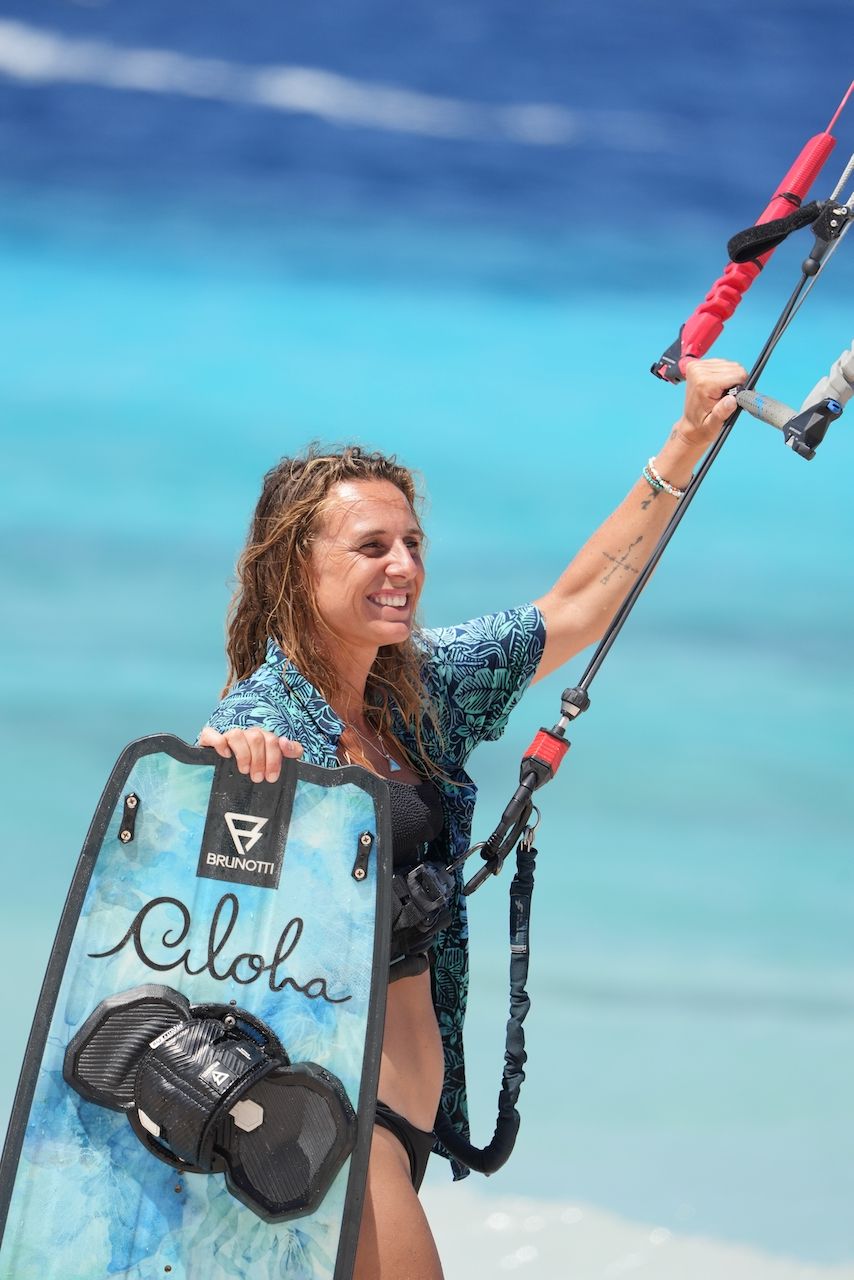 A woman is holding a surfboard on the beach.