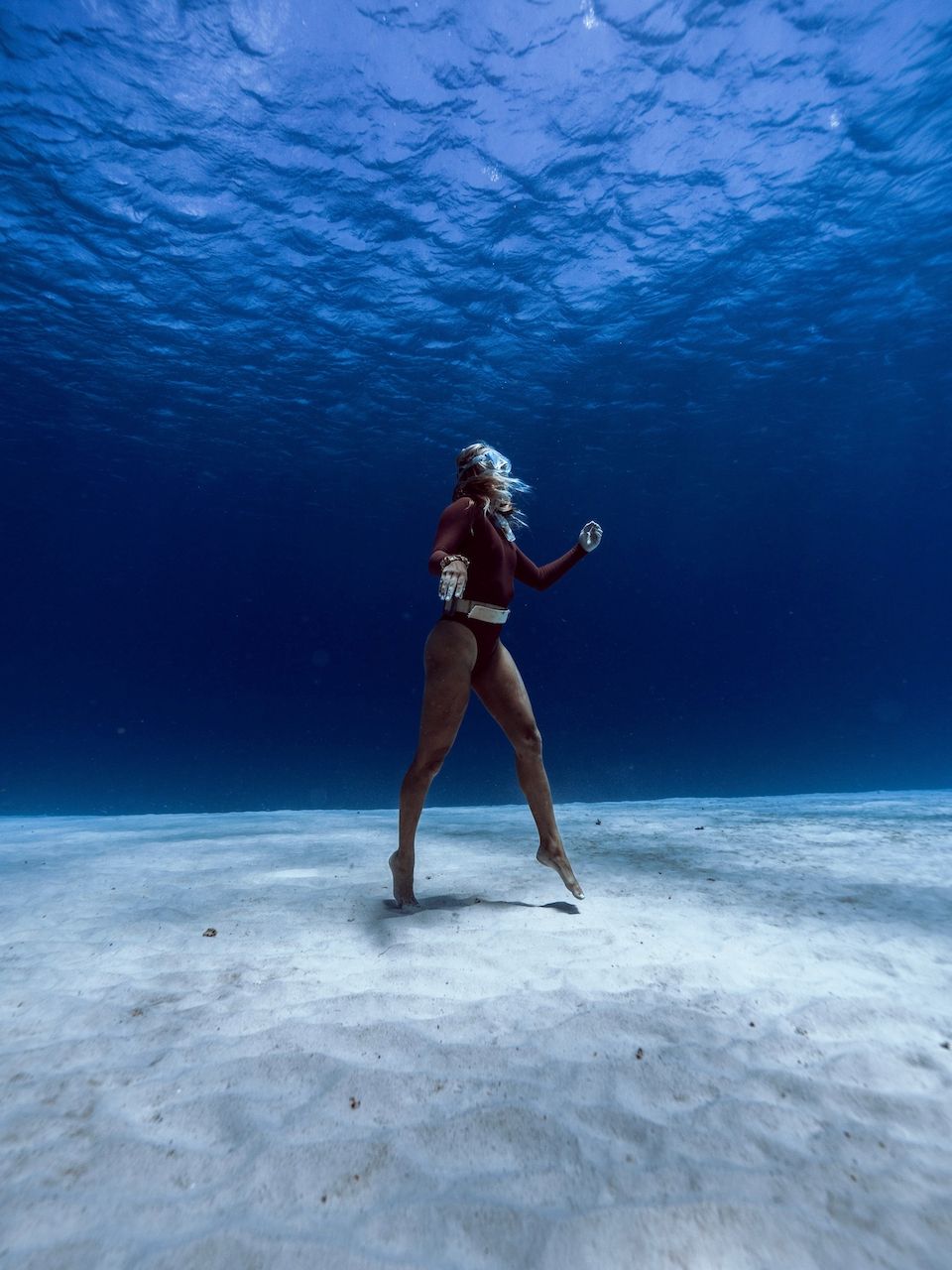 A woman is dancing underwater in the ocean