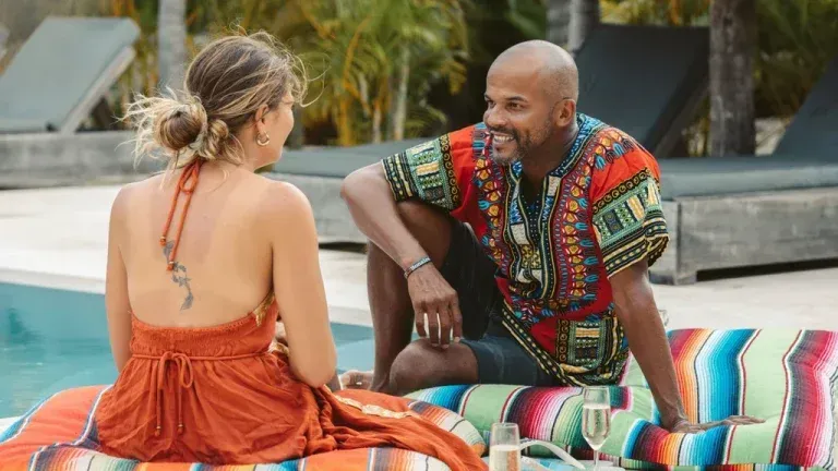 A man and a woman are sitting on a blanket next to a pool.