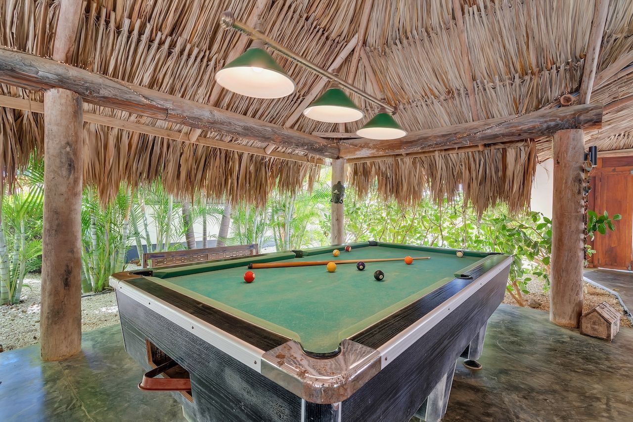 Hay una mesa de billar bajo un techo de paja.