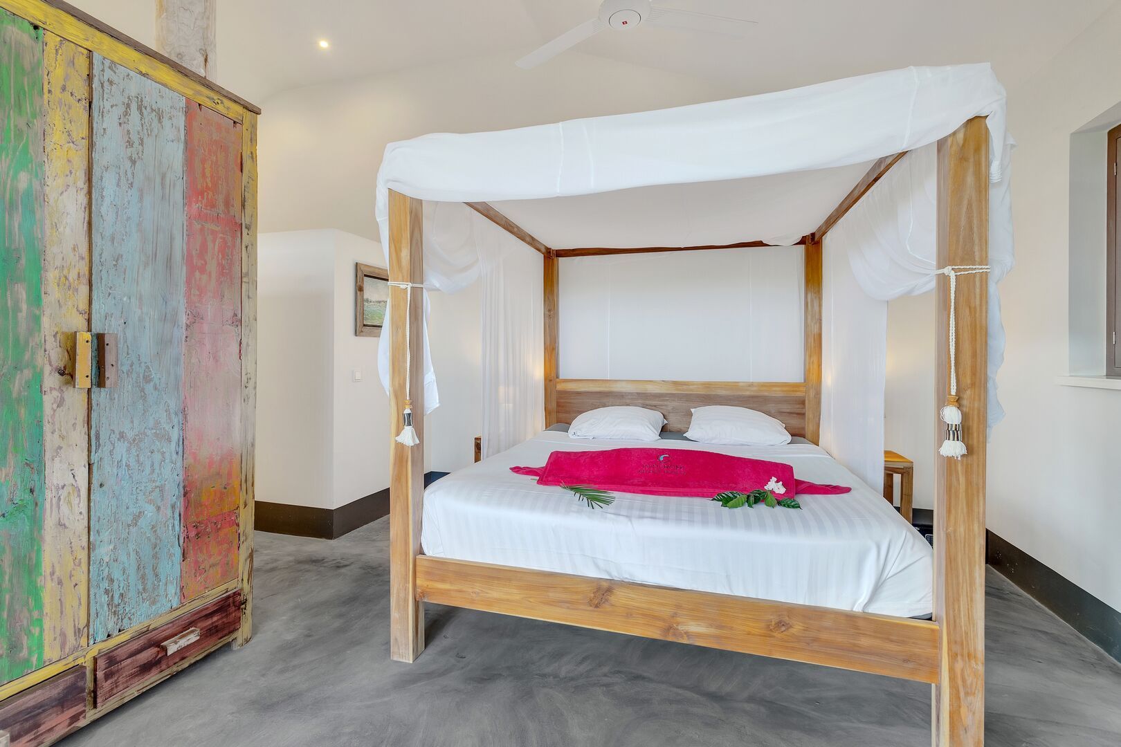 A bedroom with a canopy bed and a colorful wardrobe.