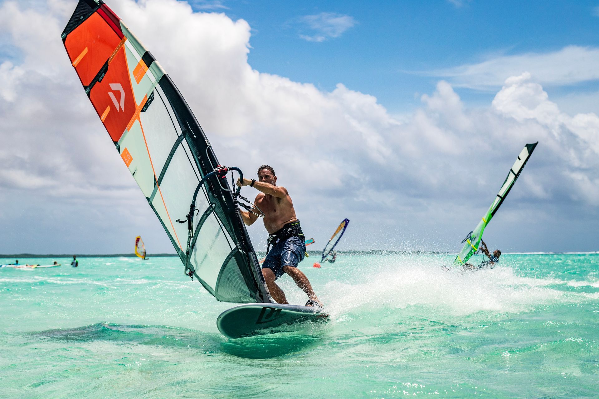 A man is windsurfing in the ocean on a sunny day.