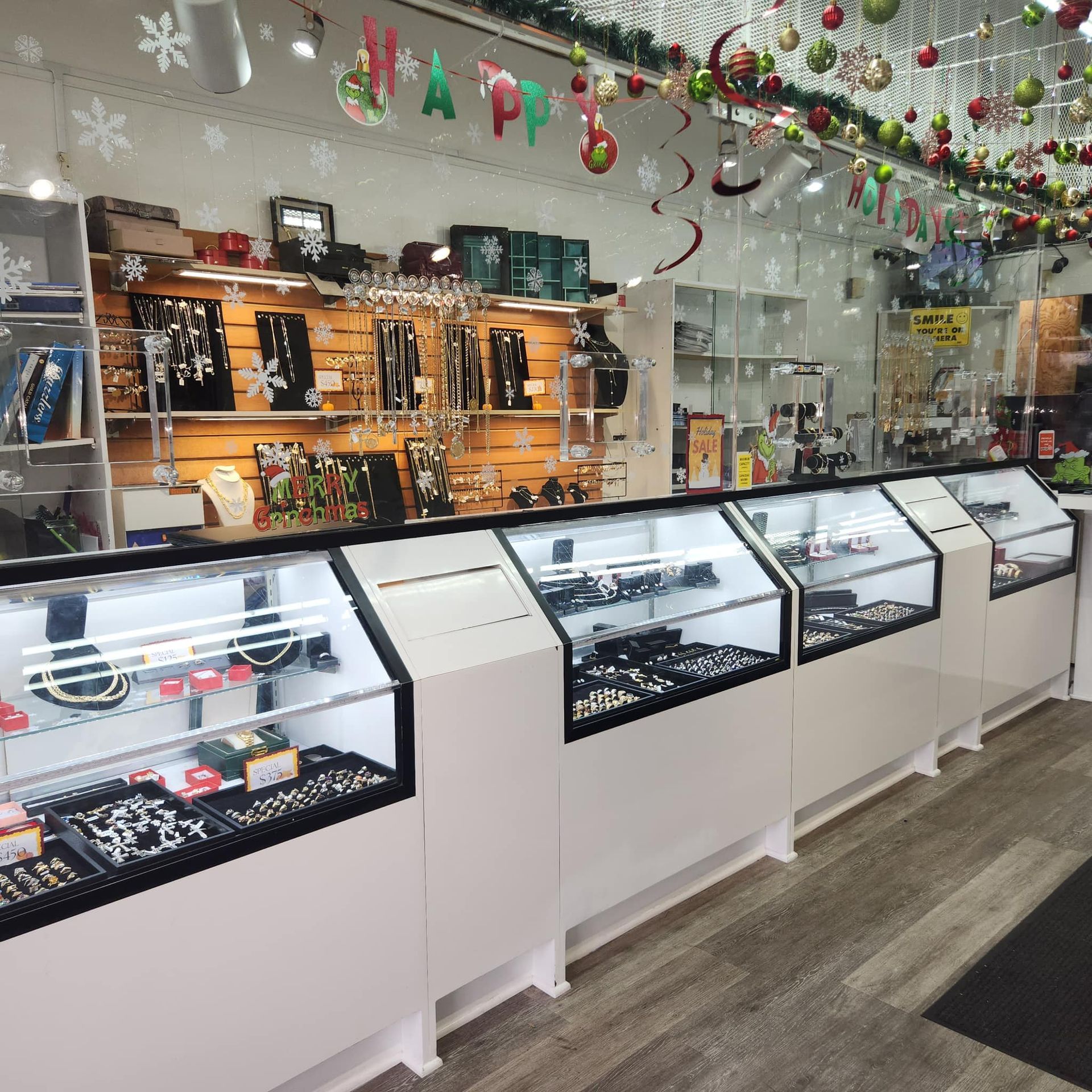 A jewelry store interior featuring white glass display cases stocked with rings and necklaces under holiday decorations.