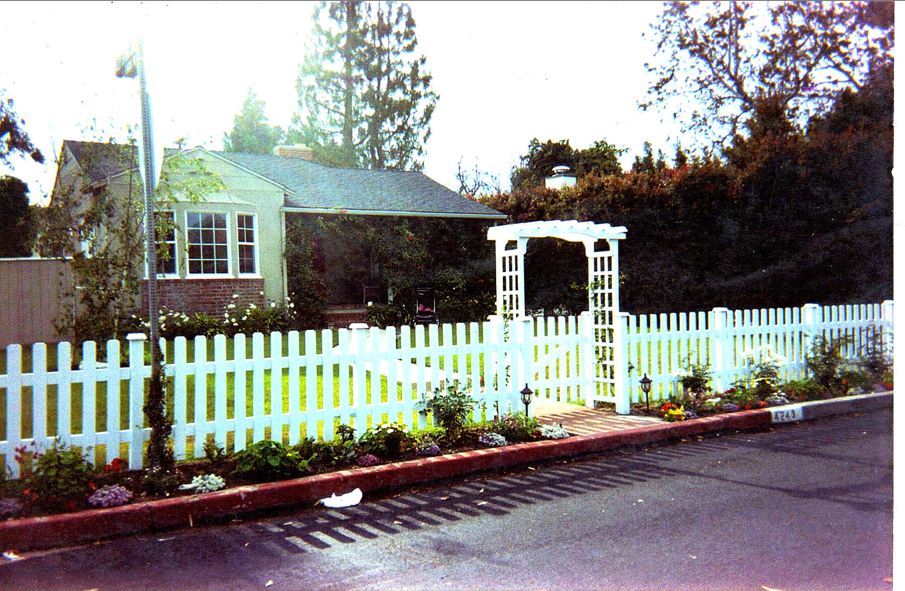 A white picket fence is in front of a house